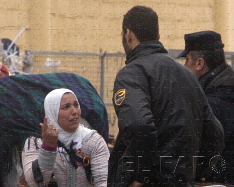 Una porteadora conversa con un auxiliar y un policía nacional.