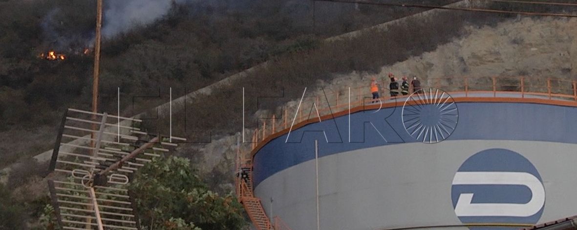 Miembros de Dúcar y Bomberos, sobre uno de los depósitos, temerosos por la aproximación del fuego.