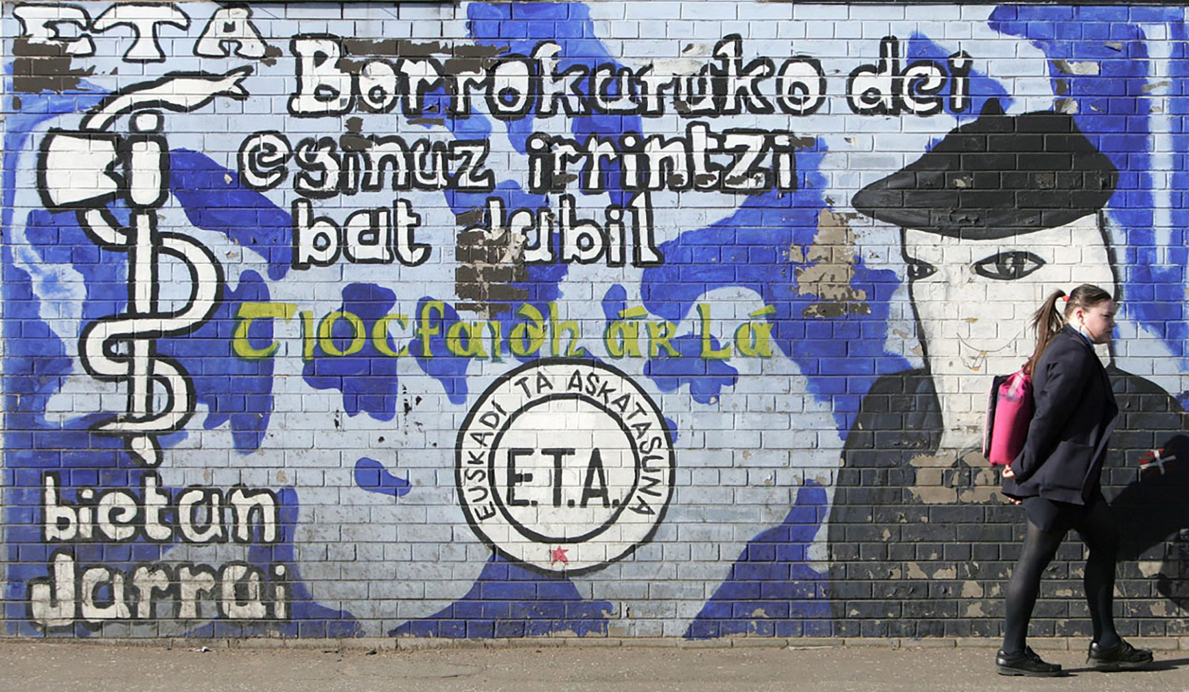 BEL02 BELFAST (REINO UNIDO) 22.03.06 Una joven pasa ante un mural alusivo a ETA en el barrio Falls Road de la zona occidental de Belfast, en Irlanda del Norte (Ulster), hoy miércoles 22 de marzo de 2006. Tras el comunicado de ETA, declarando un alto el fuego permanente, el presidente del Sinn Fein Gerry Adams declaró que el anuncio de "alto el fuego permanente" de ETA ofrece una "oportunidad de proporciones históricas" para resolver el conflicto en el País Vasco. EFE/Paul Mcerlane