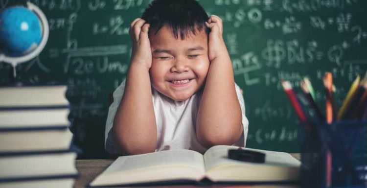 worried boy In classroom with hands on head