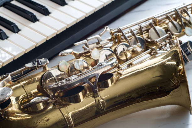 Rusty old classical saxophone on marble table next to electric piano keyboard