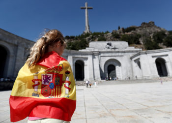 GRAF8433 MADRID (Comunidad de Madrid), 21/8/2018.-Una persona envuelta en una bandera en la explanada del Valle de los Caídos. El Gobierno aprobará el próximo viernes un decreto que modificará la Ley de Memoria Histórica para permitir la exhumación de los restos mortales de Francisco Franco del Valle de los Caídos, un polémico monumento que el dictador ordenó erigir.El ministro de Cultura y Deporte, José Guirao, confirmó hoy esa medida, aunque al tratarse de un decreto ley tendrá que ser validado por el Parlamento, lo que no ocurrirá al menos hasta septiembre.EFE/Mariscal